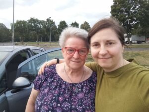 zwei Frauen stehen an einem Auto auf der Autobahn (sichtlich ein Rastplatz)